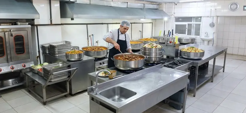 Aşçı kazandan tabaklara yemek dolduruyor